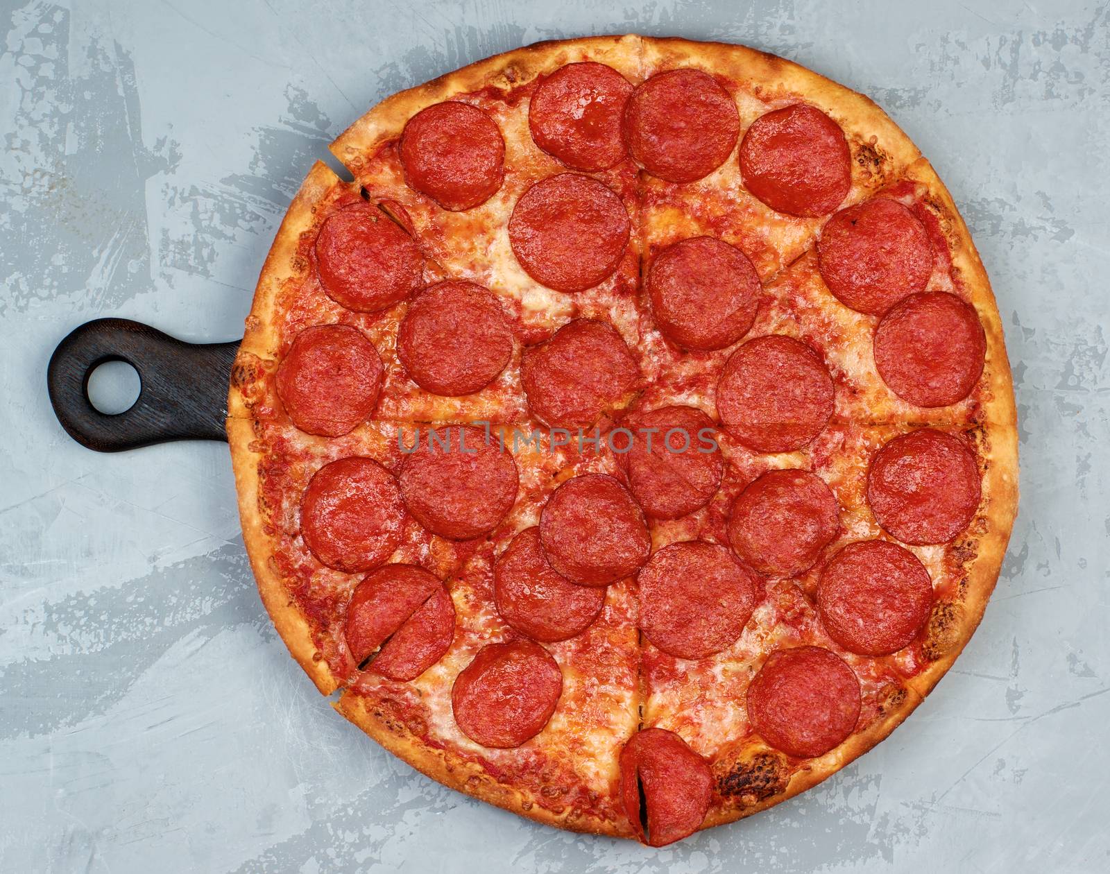Freshly Baked Pepperoni Pizza with Tomato Sauce, Pepperoni and Cheese on Cutting Board on Grey Textured background. Top View