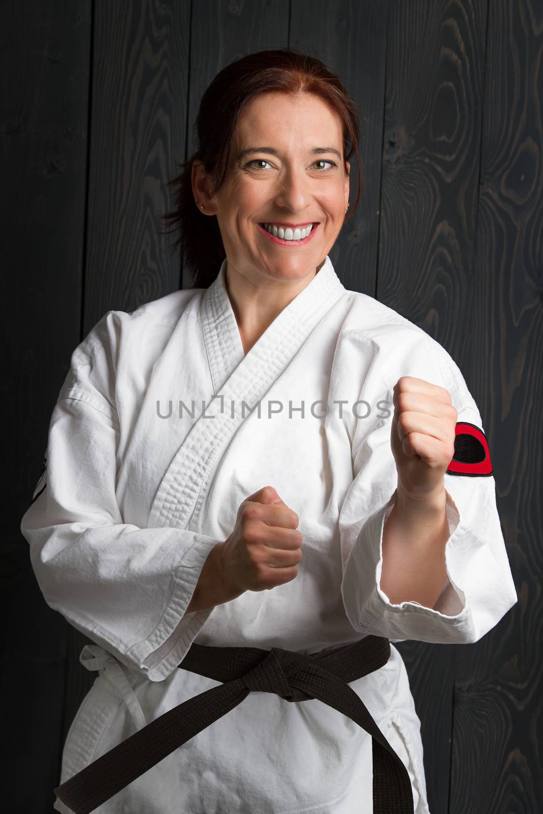 forty year old woman wearing karate gi in punching stance and a great big smile