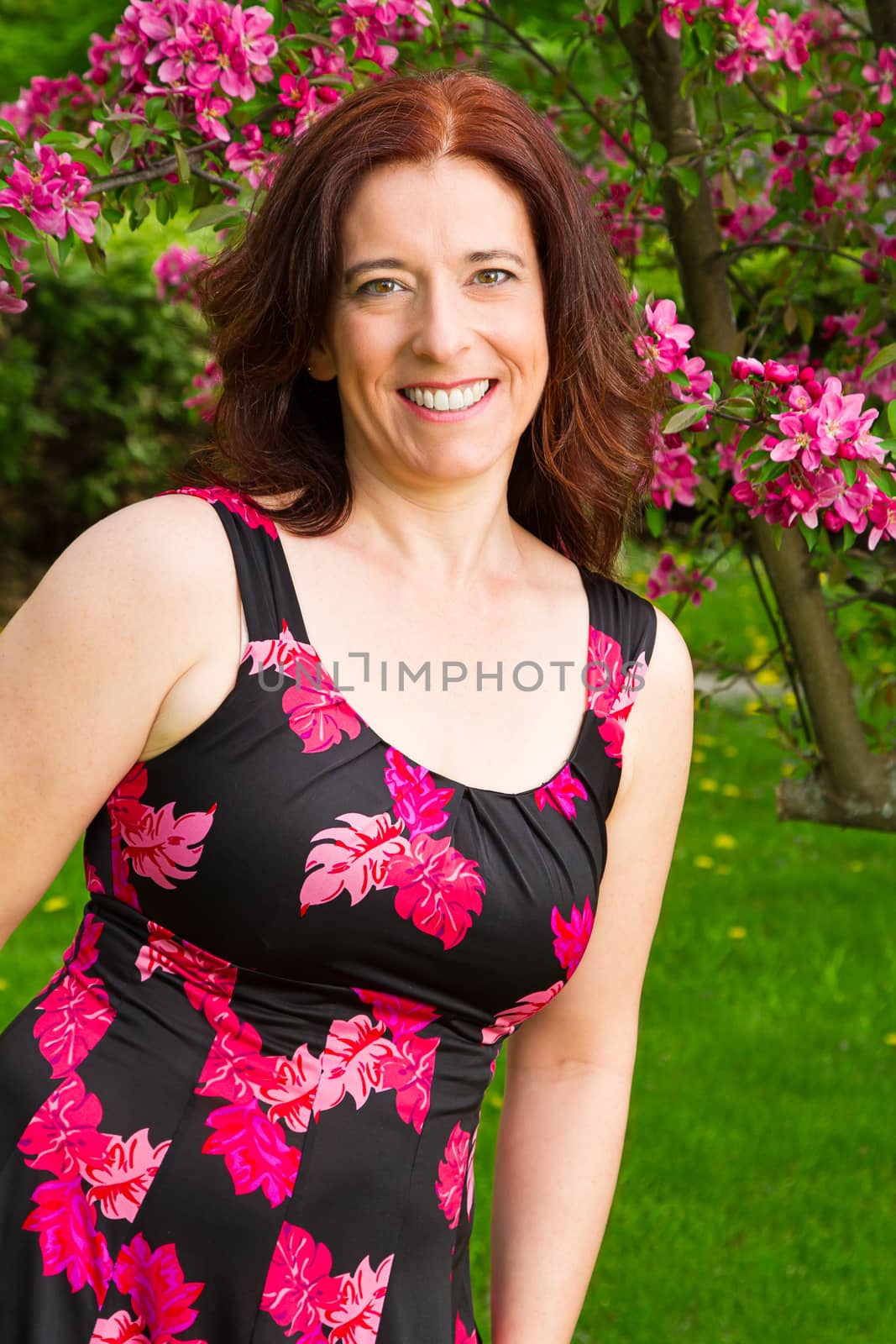 forty something brunette woman wearing a sun dress under a cherry tree