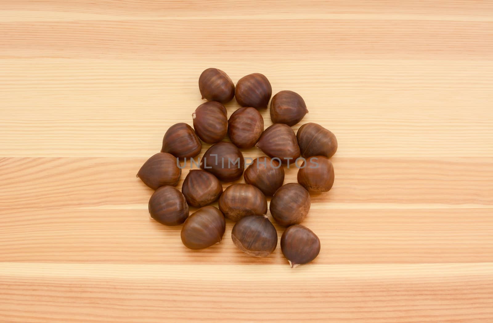 Sweet chestnuts in shells on a wooden background, pine wood grain