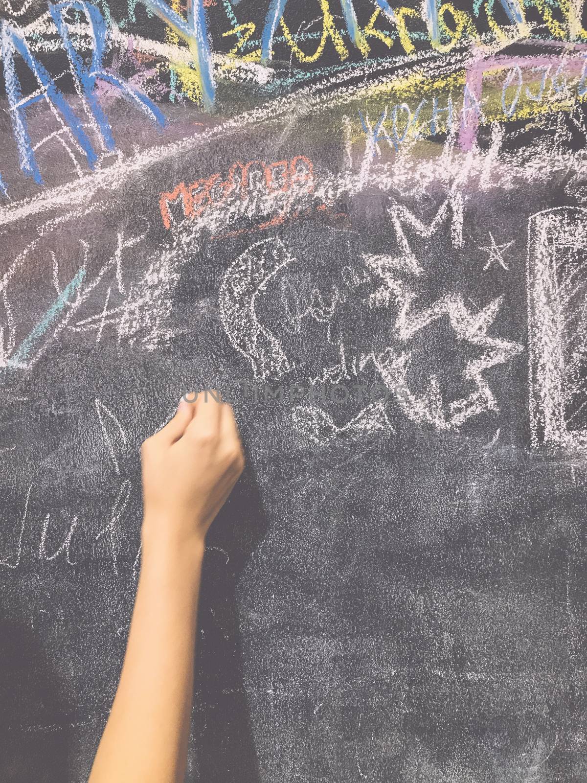 A child paints by chalk on a school board by Softulka