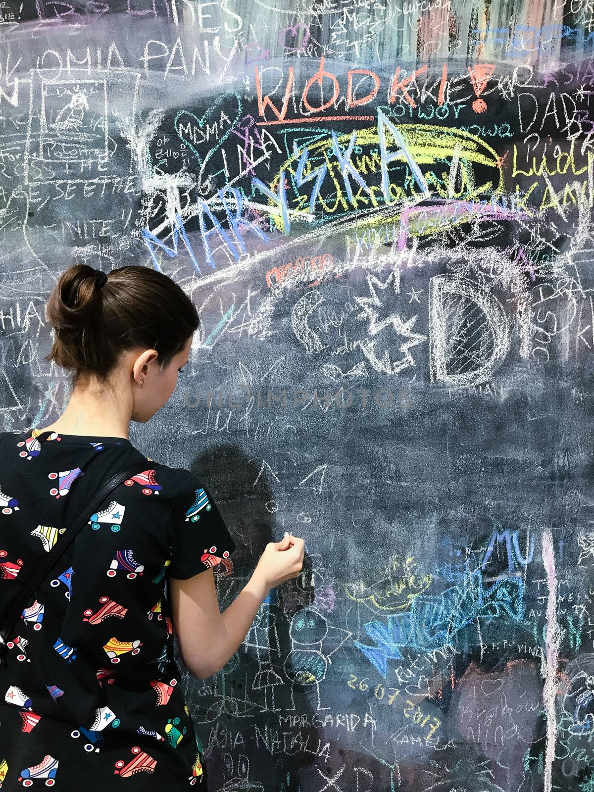Back to school. A child paints scribbles by chalk on a board