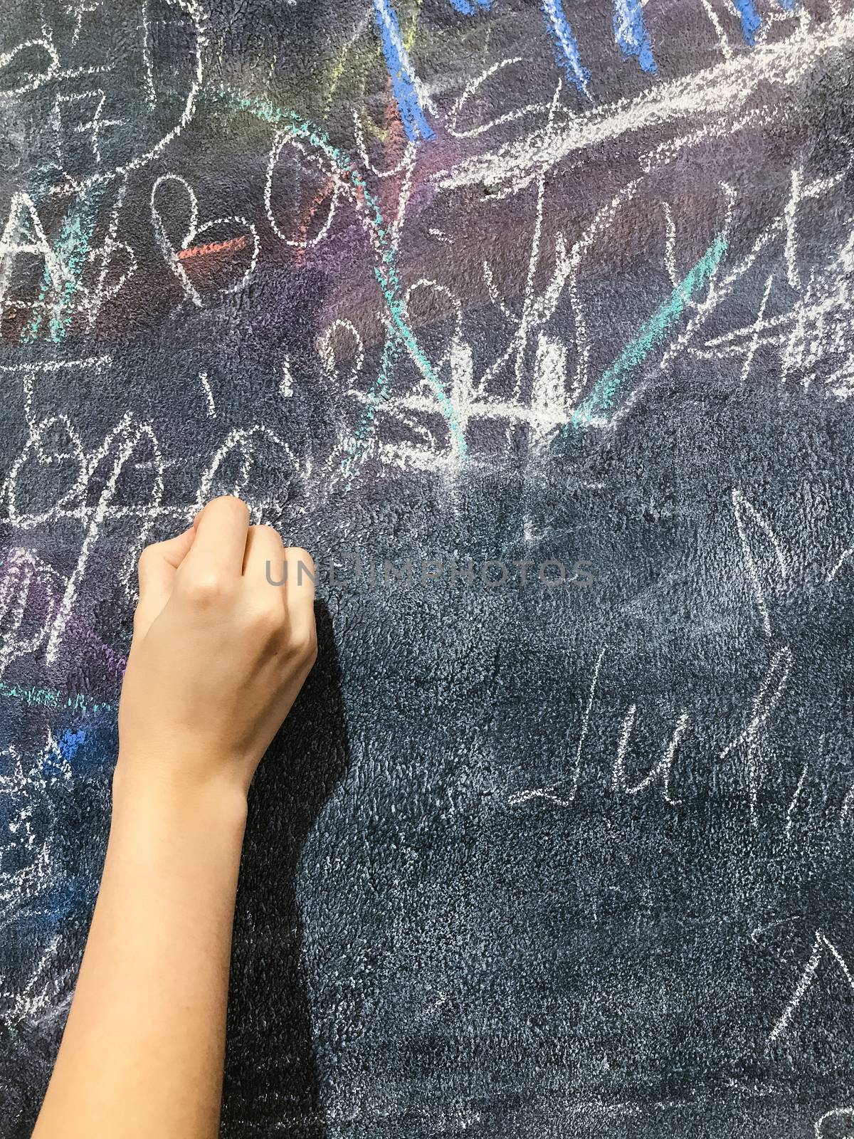 A child paints by chalk on a school board by Softulka
