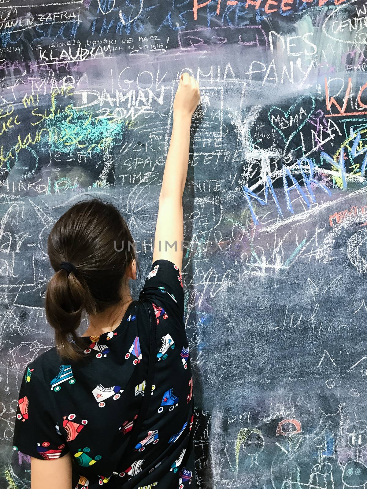 Back to school. A child paints scribbles by chalk on a board