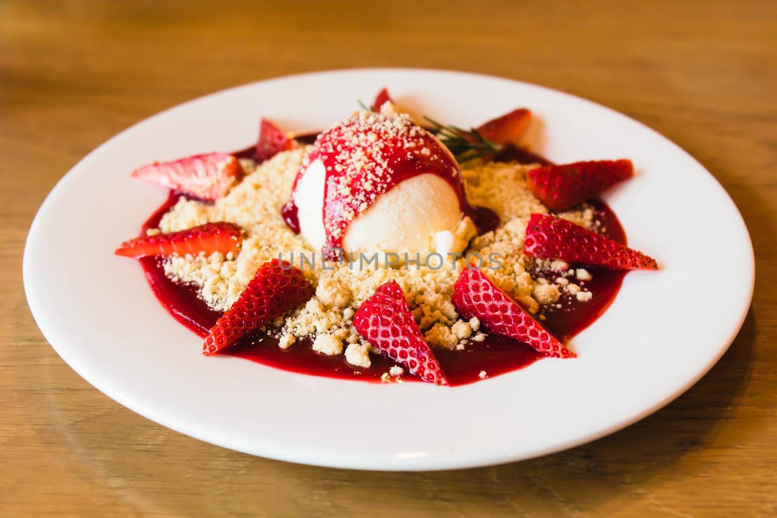 Ice cream with strawberry and cookie crumble on white dish