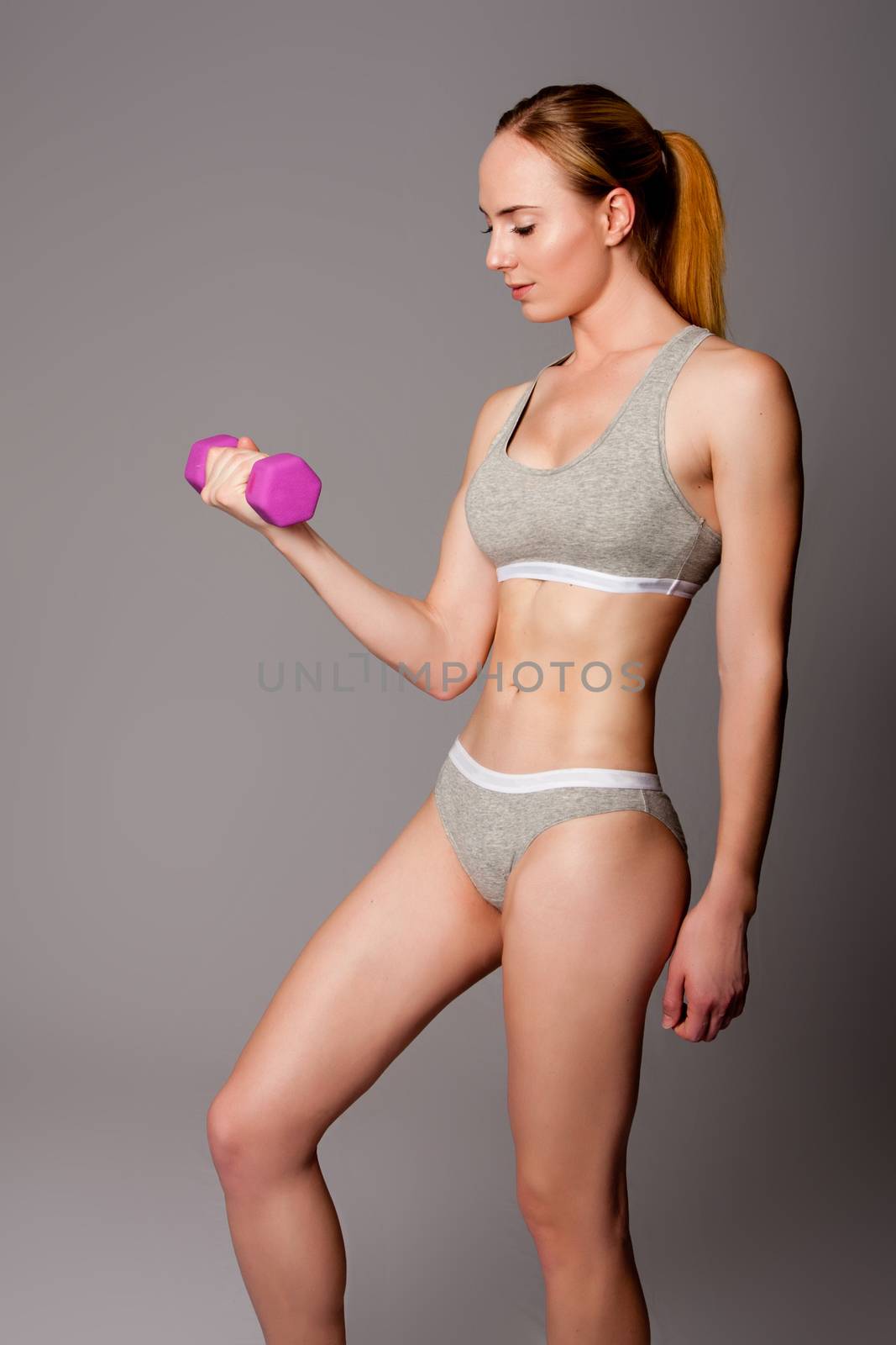 Beautiful athletic woman lifting weight dumbbell fitness workout.