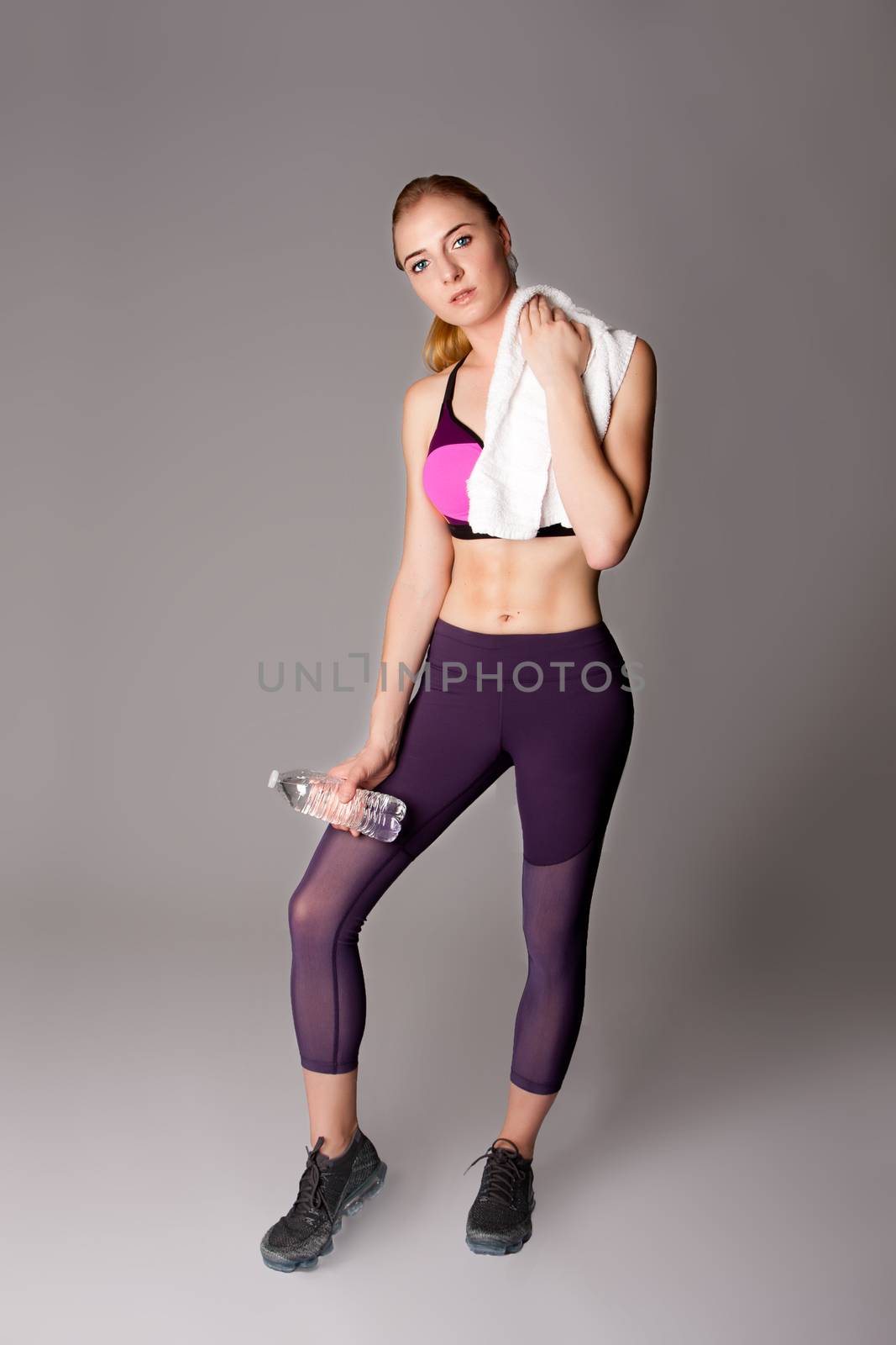 Beautiful woman standing with water and towel after healthy firness exercise.