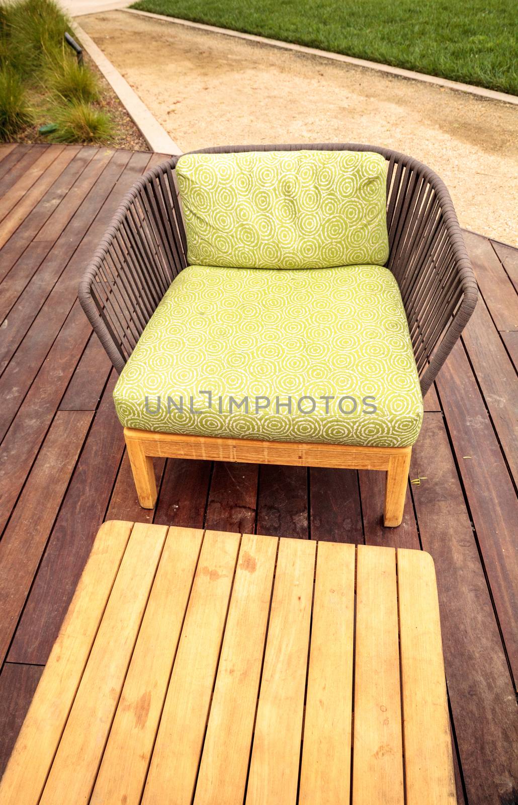 Wood patio lounge chairs with green cushions in the backyard with green grass in the summer.