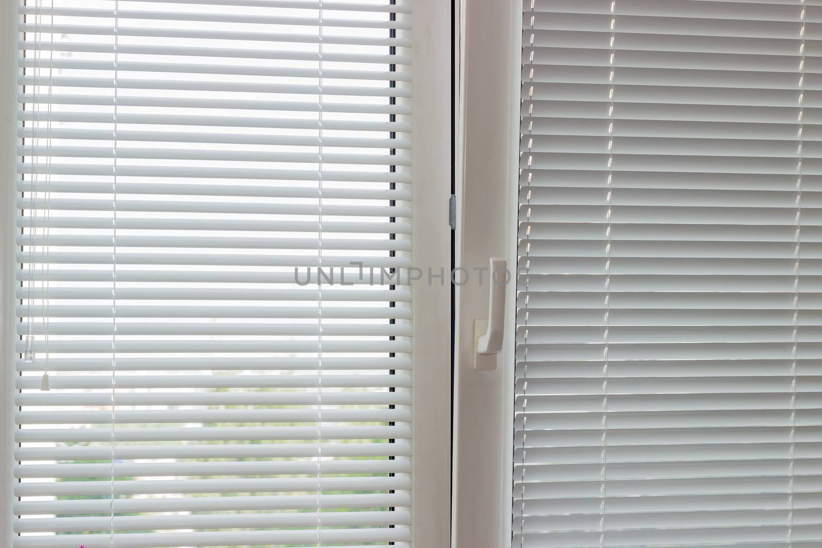 Fragment of thr modern tilt and turn plastic window with white Venetian blinds with manual control
