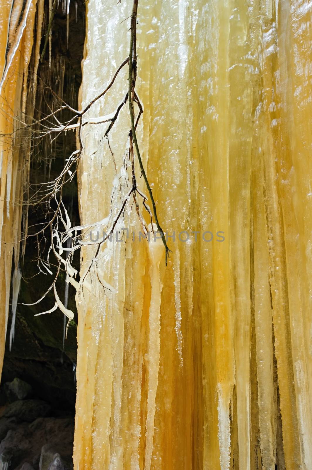 Detail frozen waterfalls on the rock, orange colored 