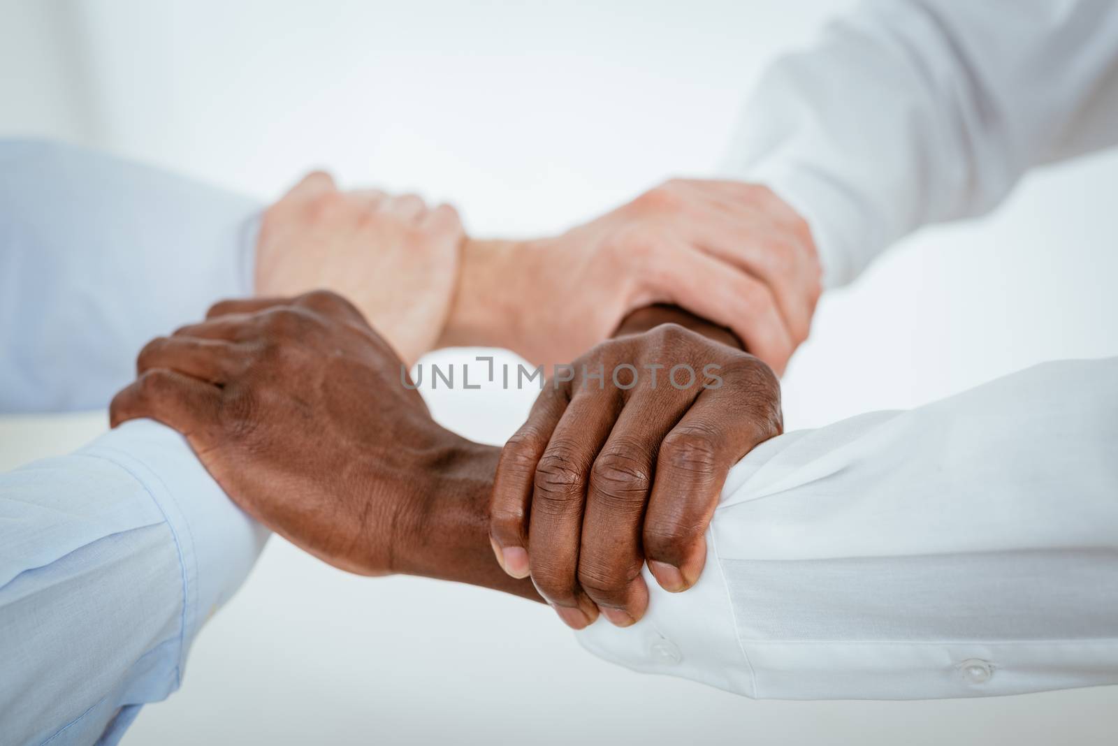 Close-up of a four black and white hands holding together tightly.