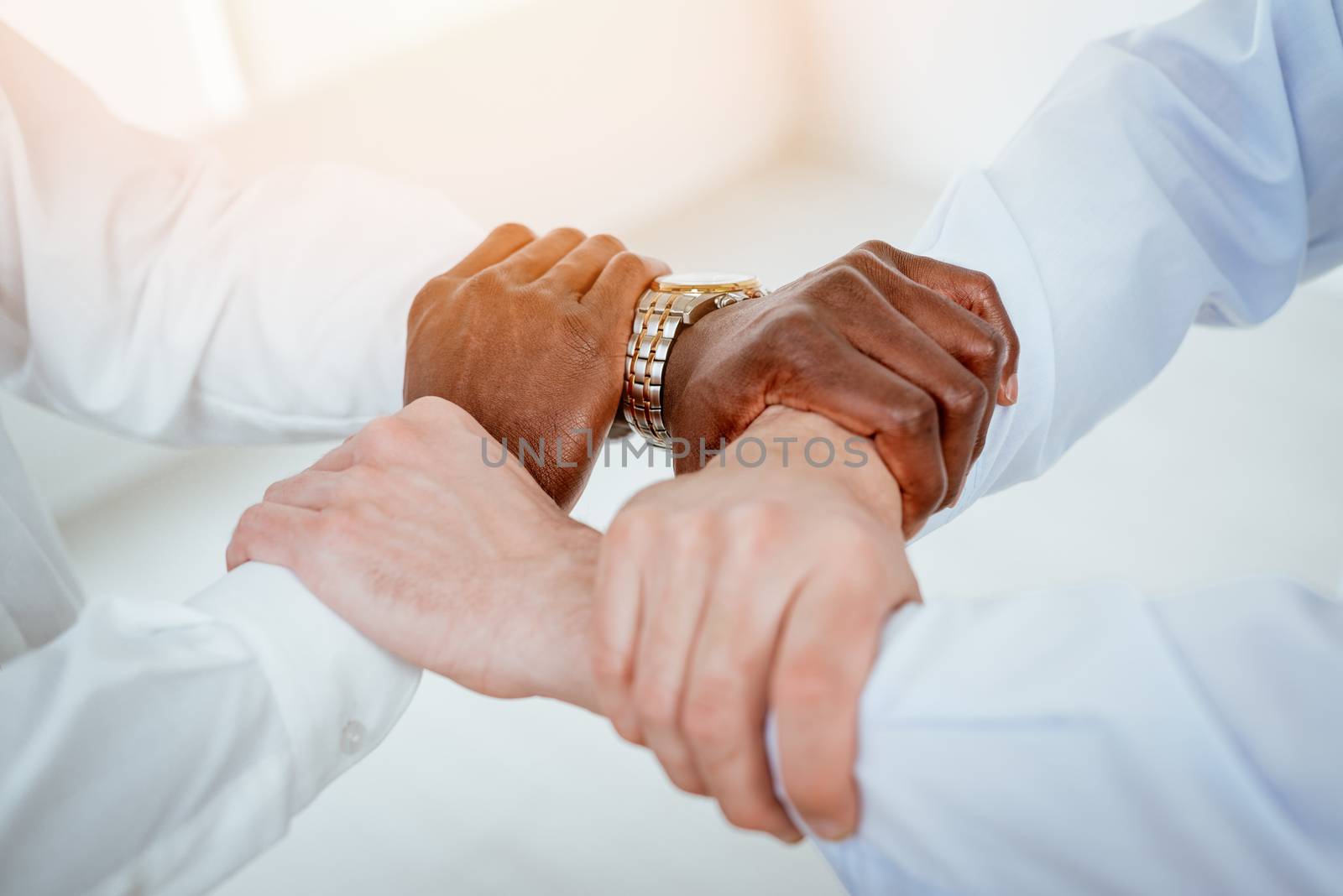 Close-up of a four black and white hands holding together tightly.