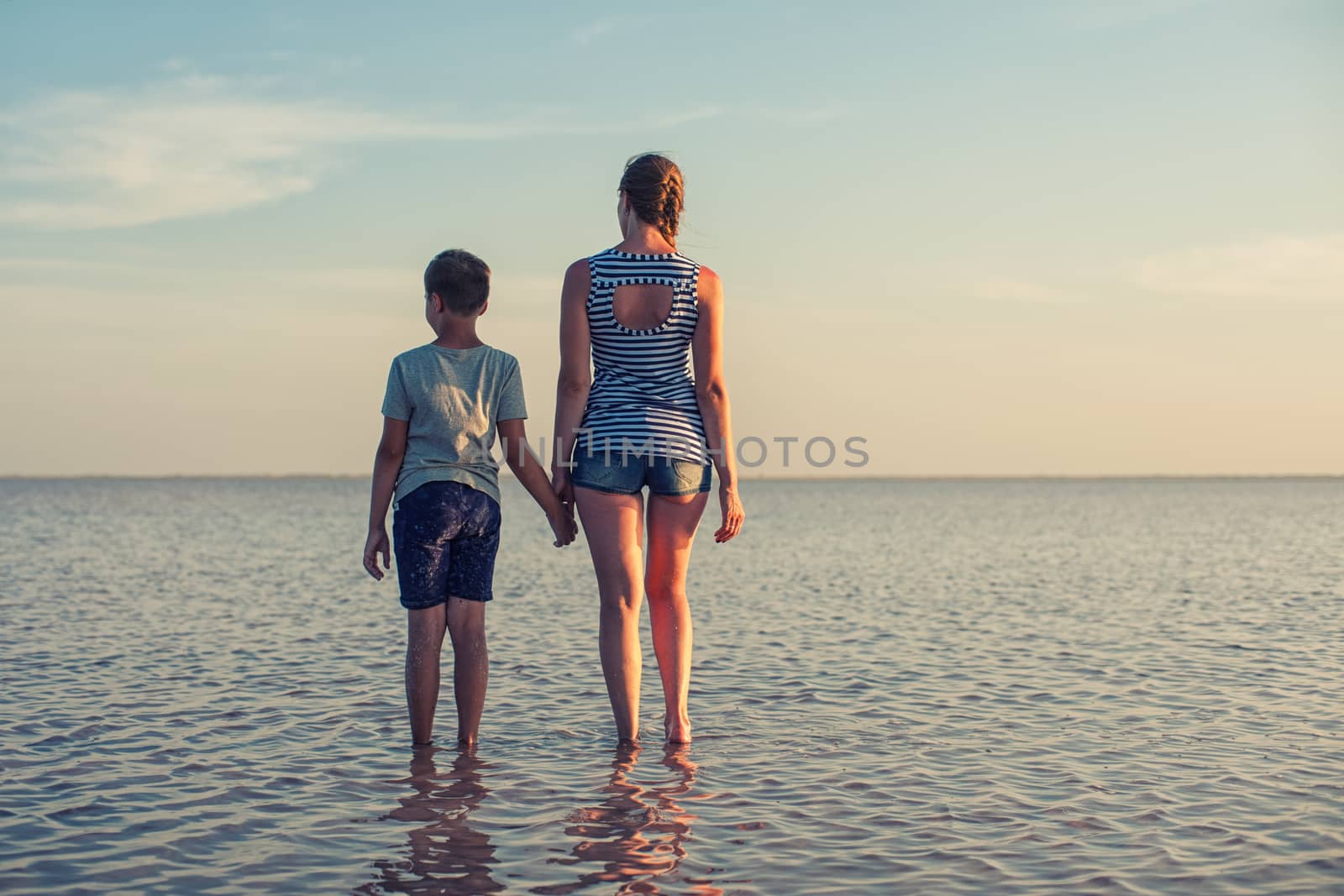 Mother and her son on salty lake with beauty sunset