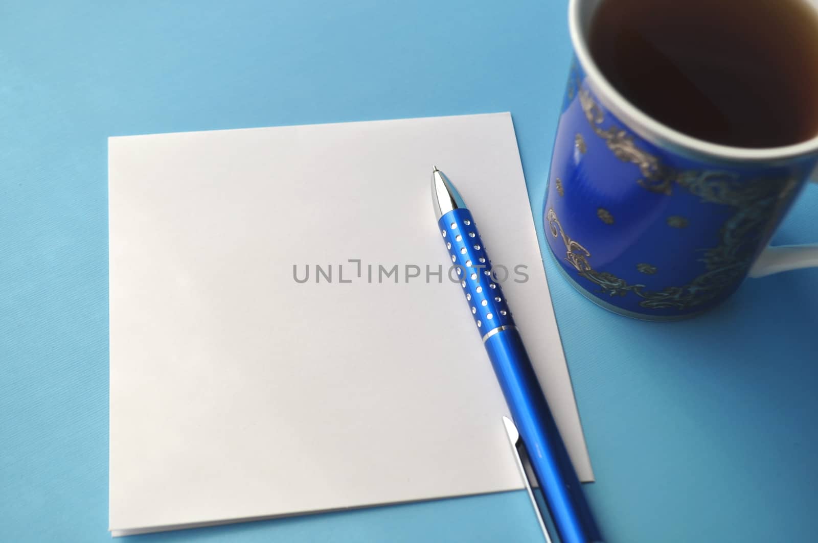 Blue porcelain cup with tea and a book on grey, white and blue background with copy space