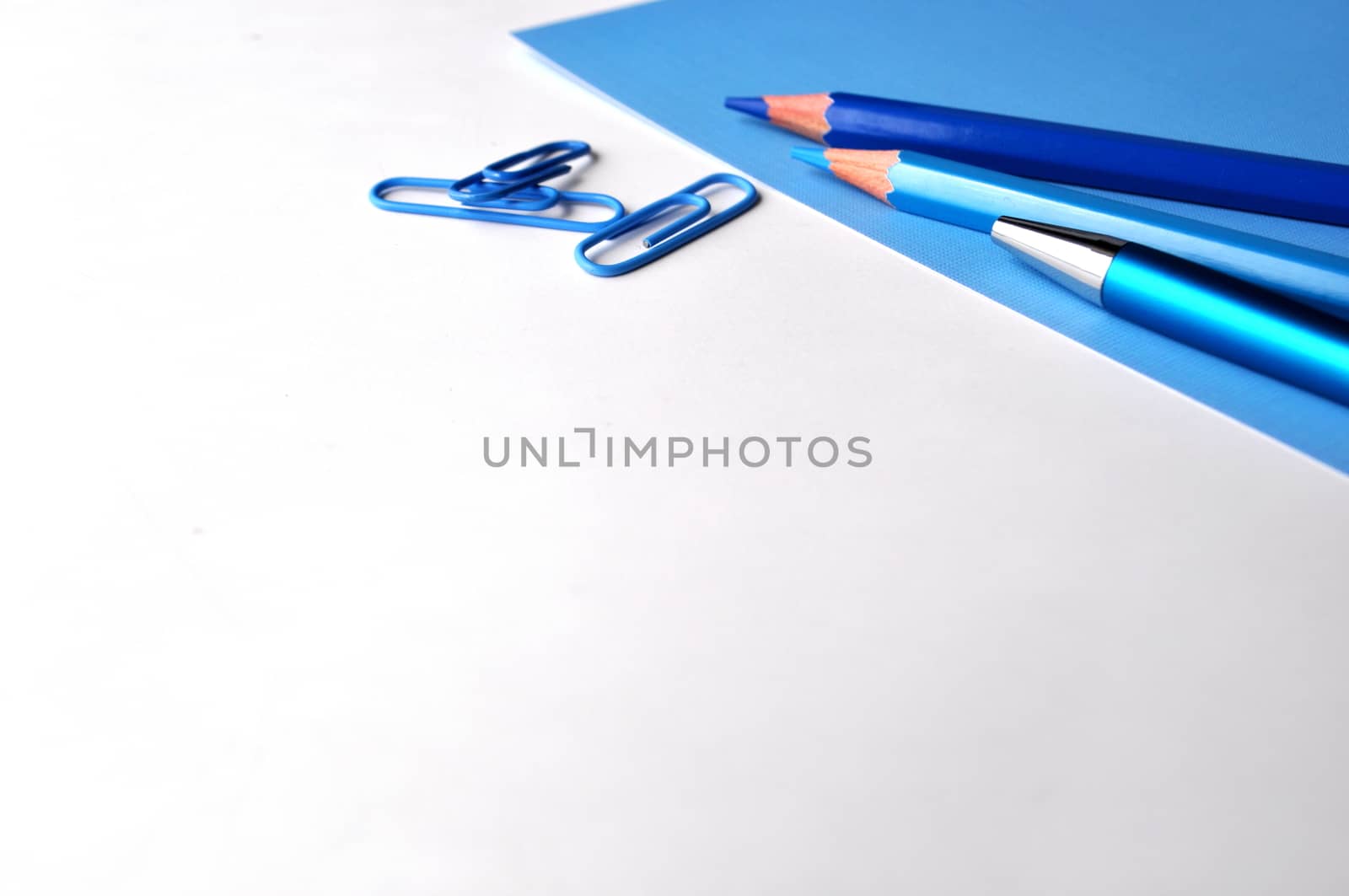 Blue pencils and a pen on white and blue with copy space by Akvals