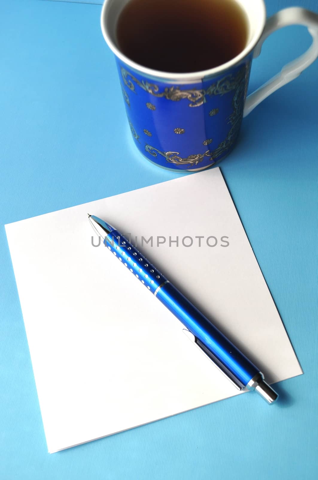 Blue porcelain cup with tea and a book on grey, white and blue background with copy space