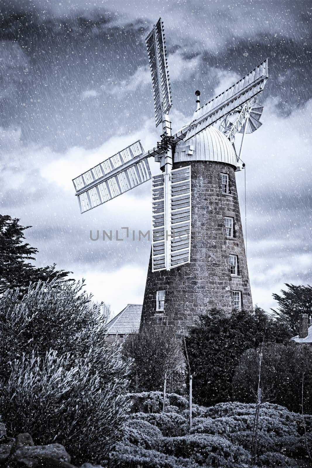 Country windmill covered in artificial rain and snow.