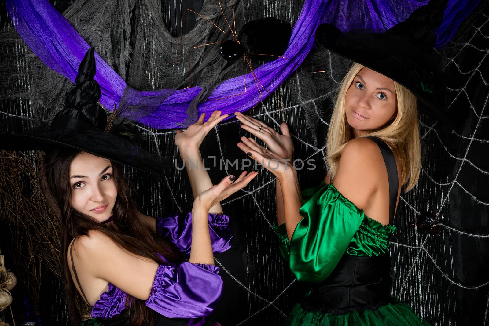 two witch girl friends show a large spider on the wall