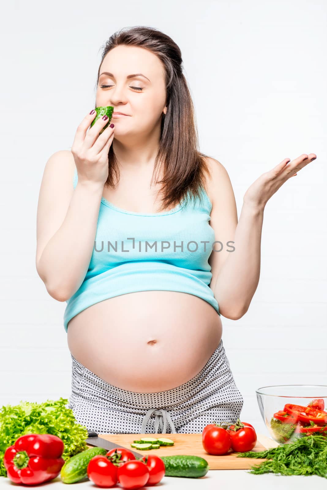 happy pregnant woman with vegetables on the table preparing a salad