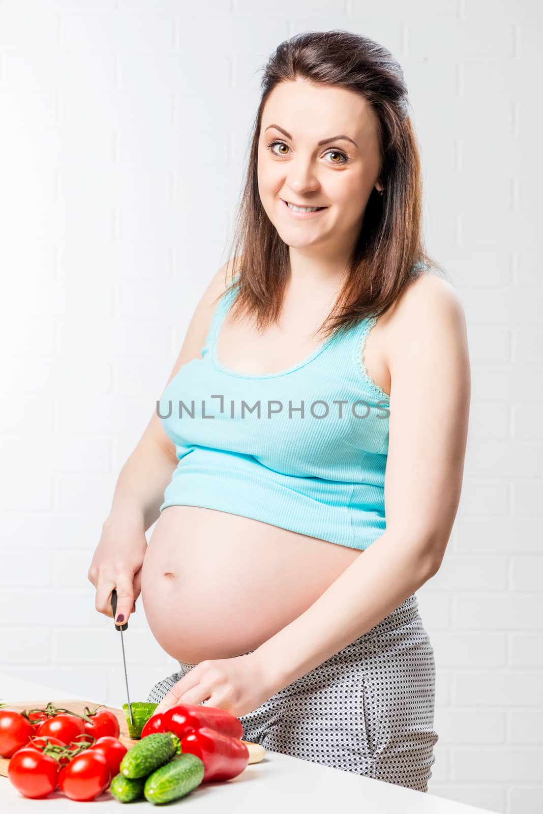 pregnant happy woman cuts fresh vegetables for lunch