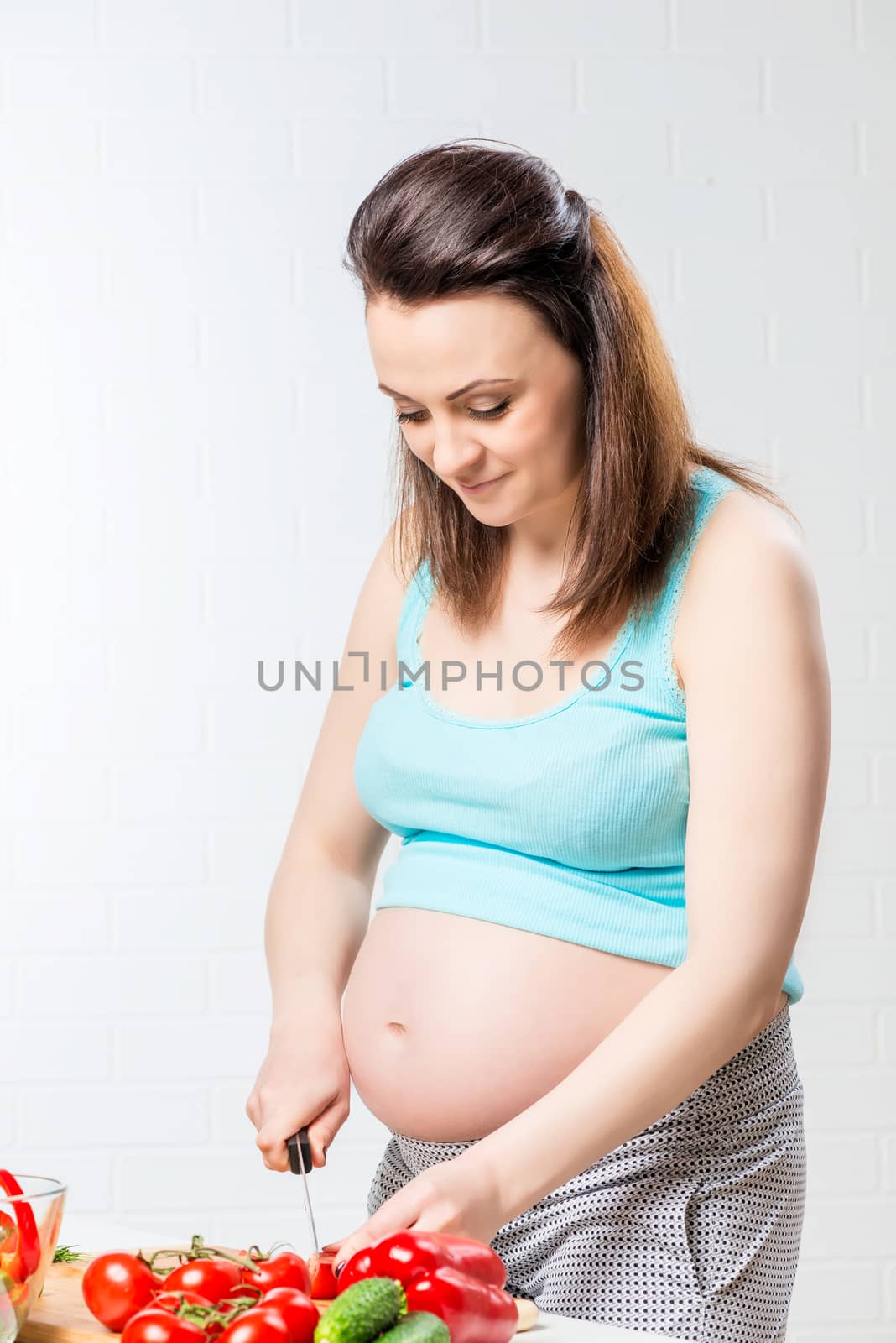 beautiful pregnant girl preparing a salad of fresh vegetables