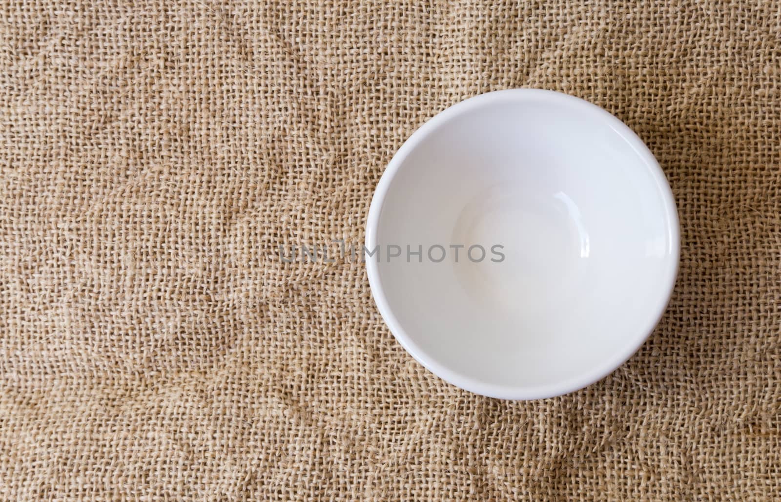 Closeup top view empty white bowl on sackcloth background texture, food concept