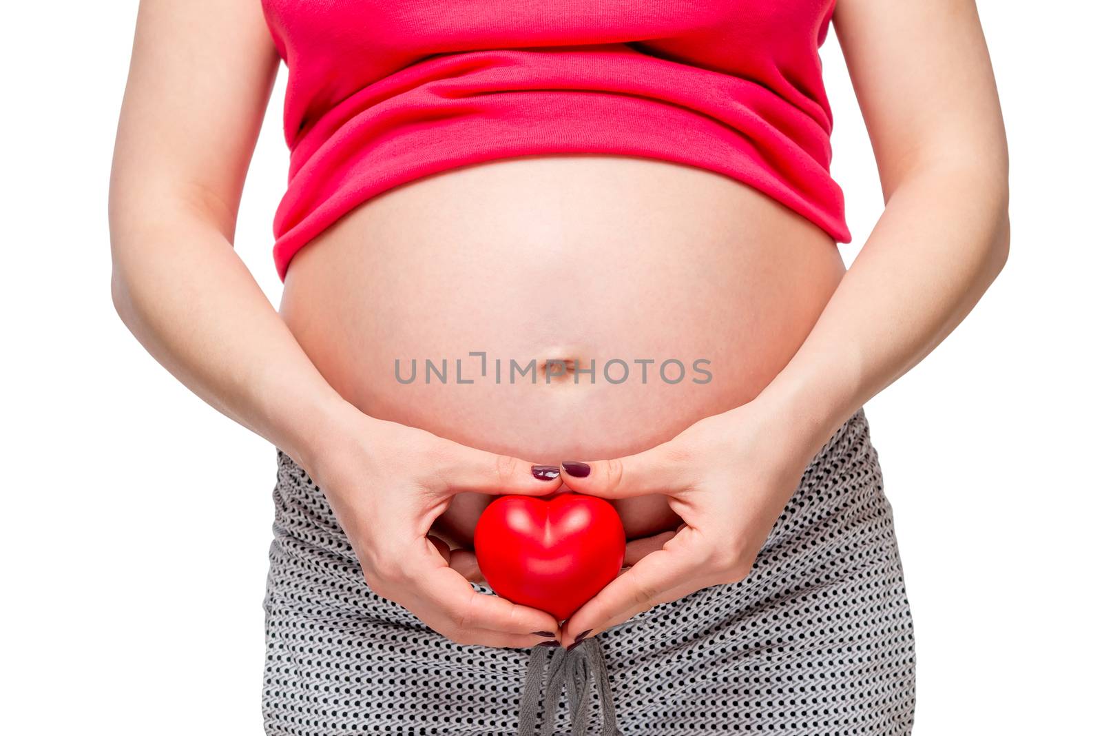 female hands holding a loving heart at the abdomen level, on a white background close-up