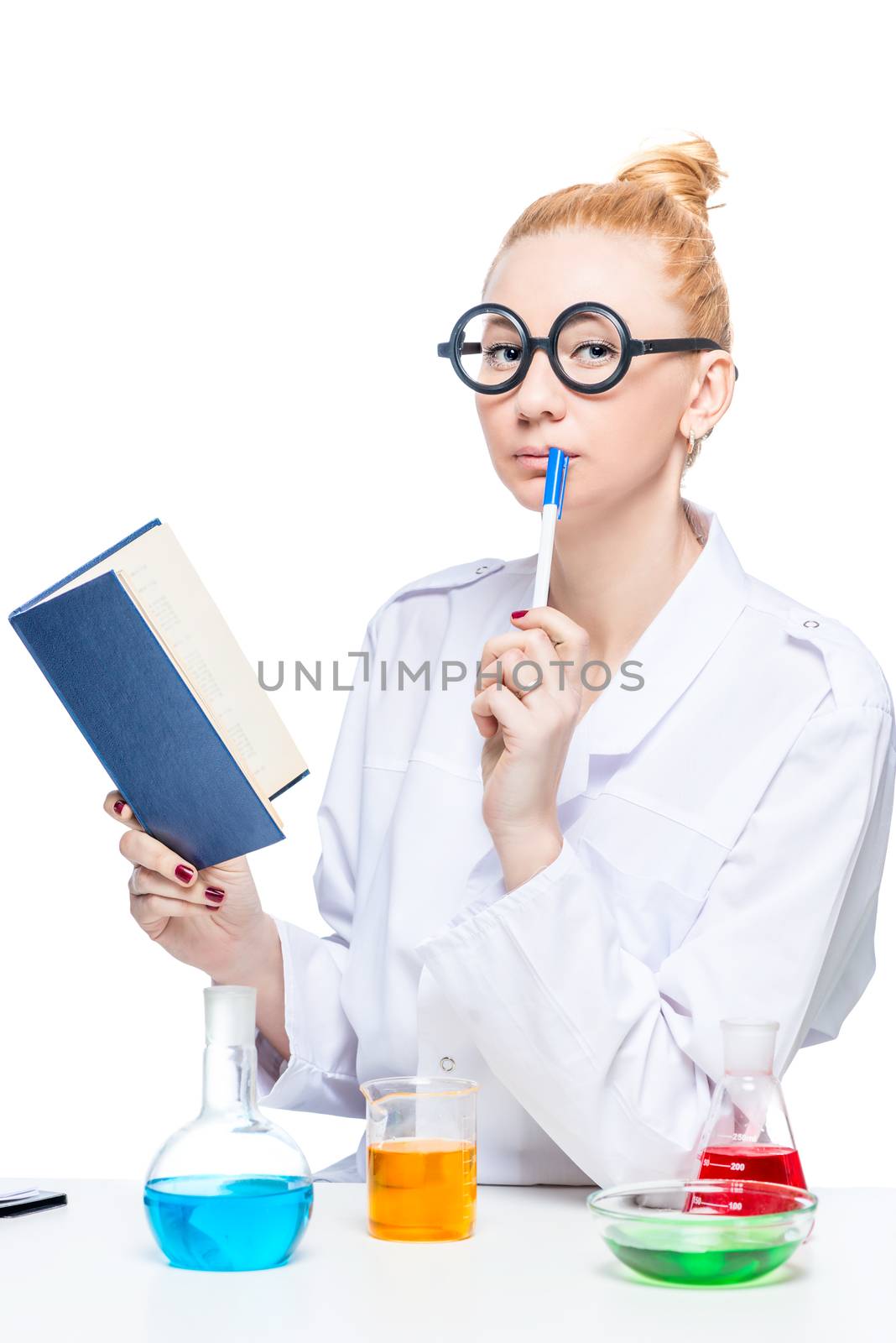 Thoughtful funny chemistry student with a book and test-tubes at the table