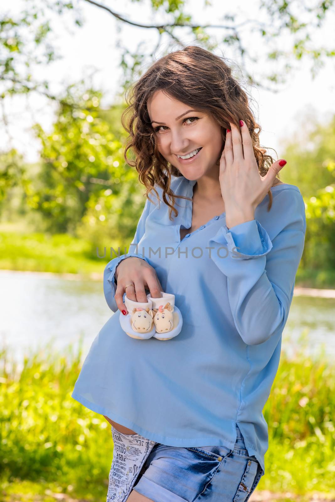 Happy pregnant woman with booties in the park