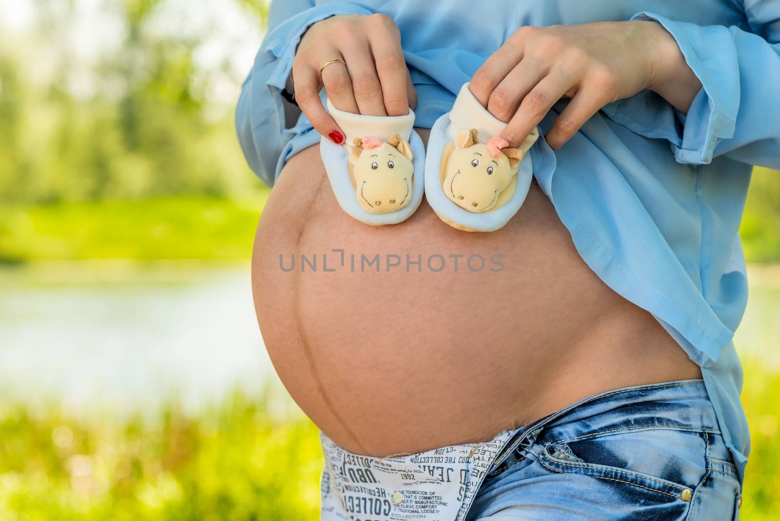 Belly of a pregnant woman close-up and booties in hands by kosmsos111