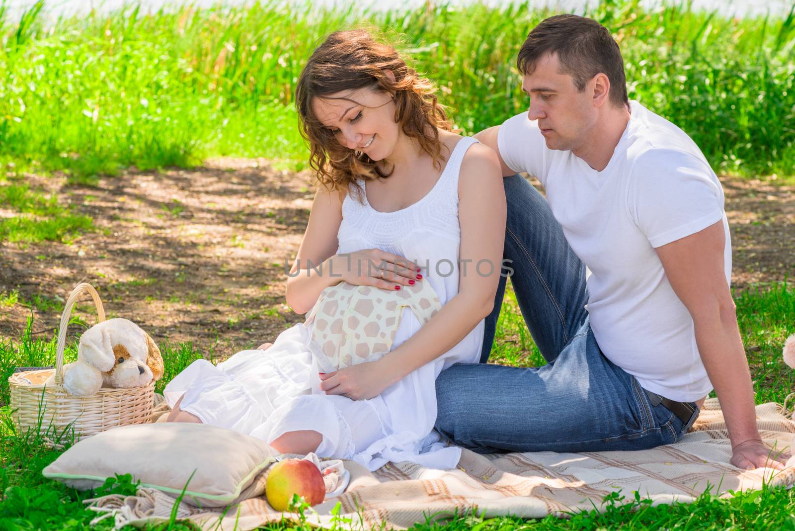 Family in anticipation of a child, rest near a lake in a park on by kosmsos111