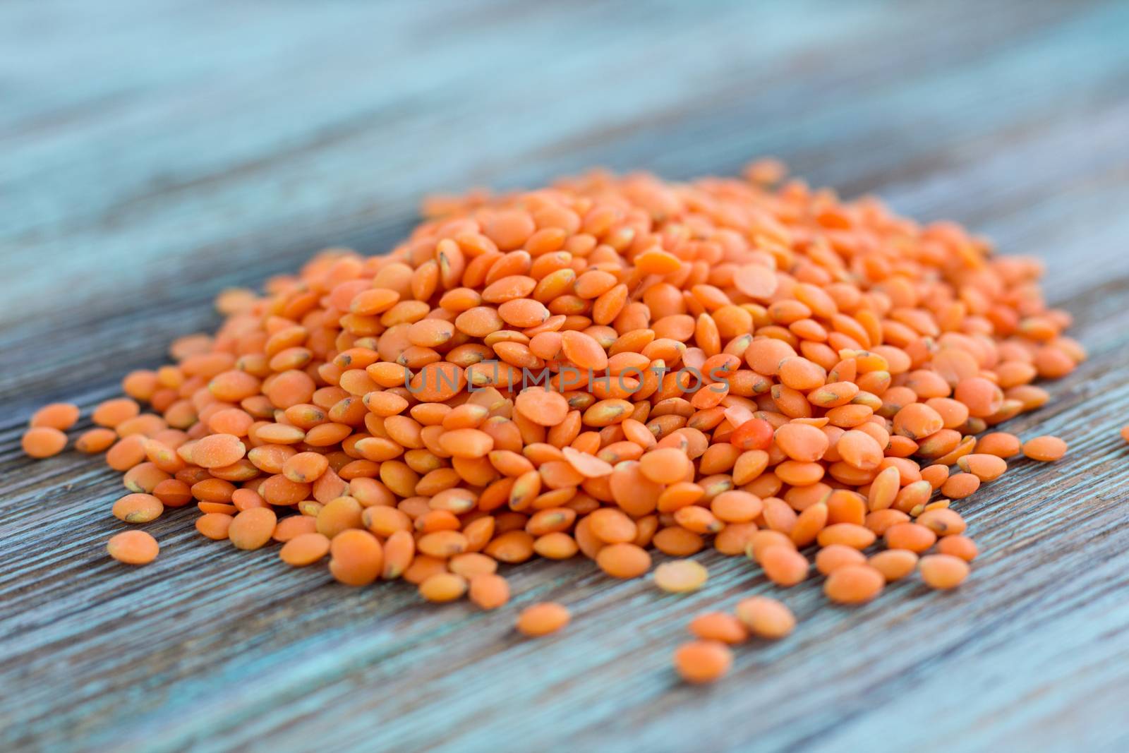 Batch of yellow lentils scattered on wooden background