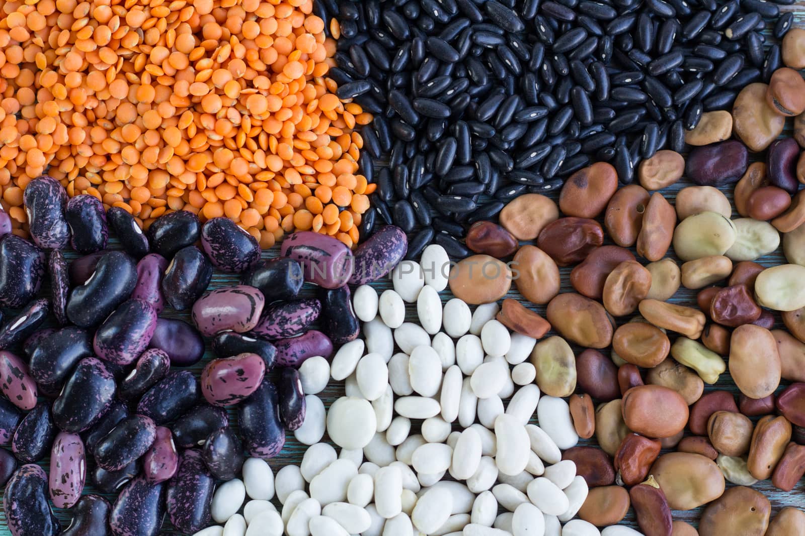 Batches of yellow lentils, white, purple, brown kidney haricot beans scattered close-up