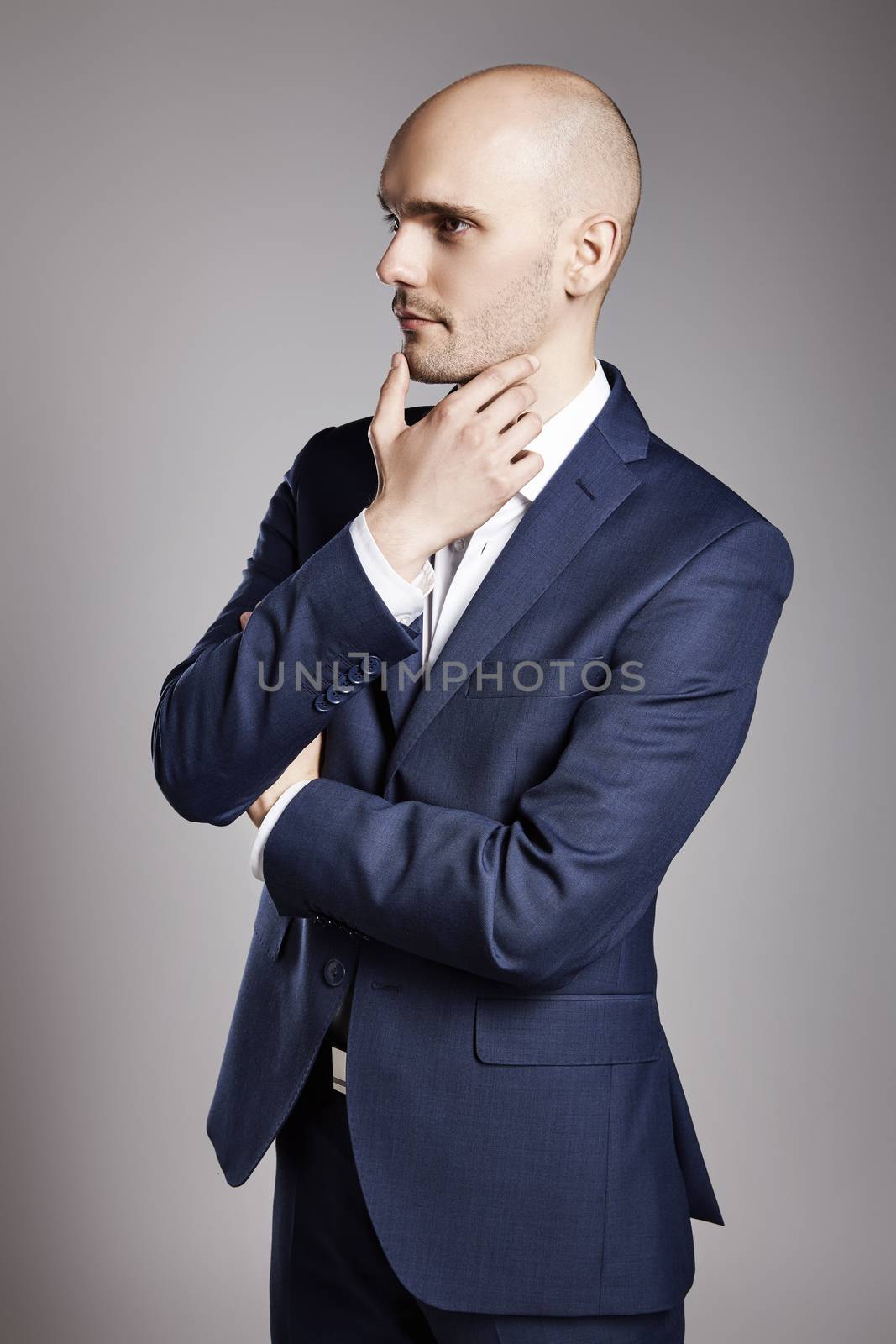 Portrait of young bald businessman looking aside.