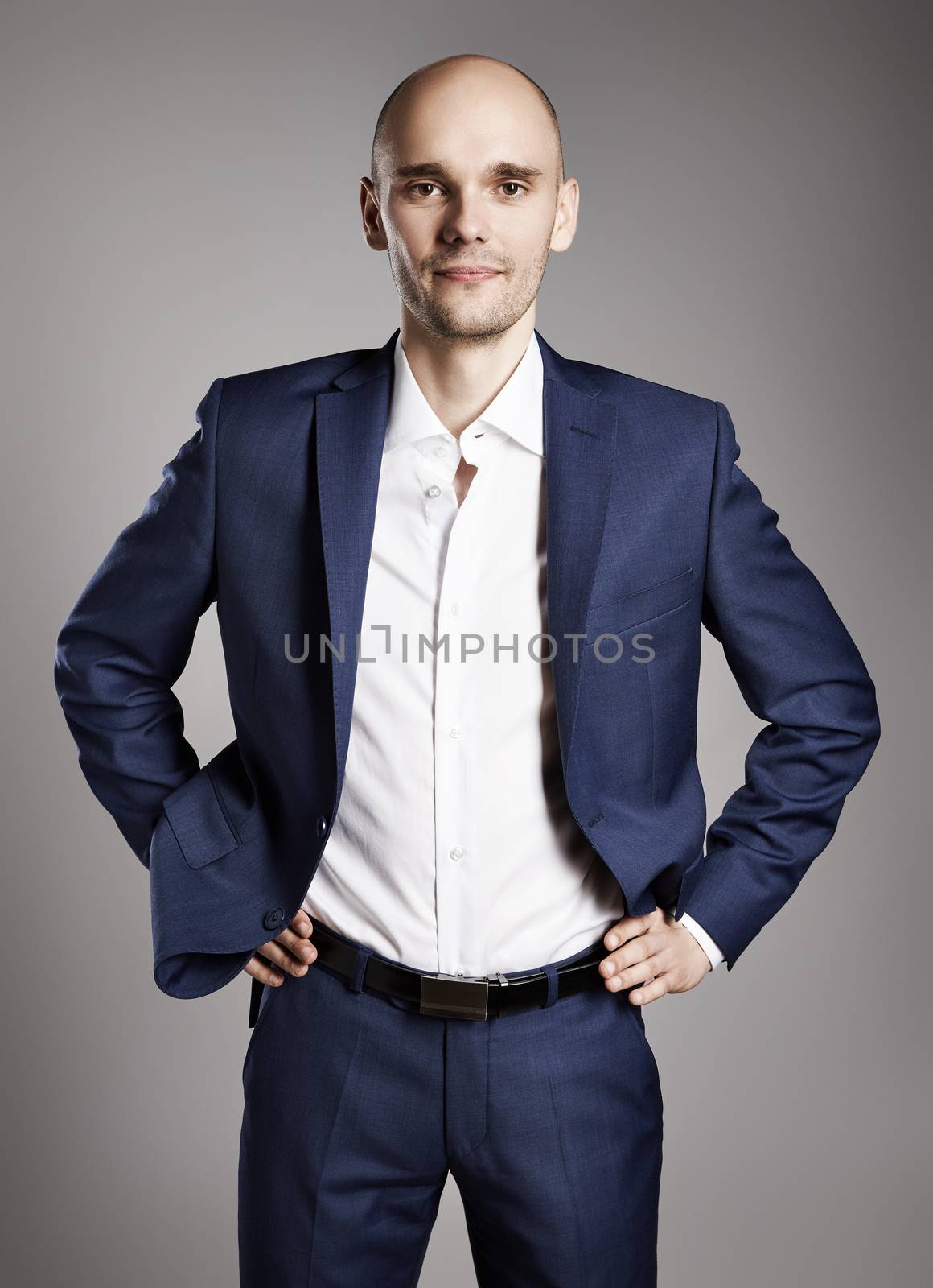 Portrait of young confident businessman on gray background.