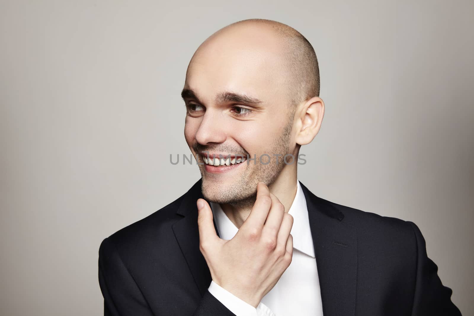 Studio shot of young smiling man. Horizontal format, he is smiling, he is wearing a black jacket.