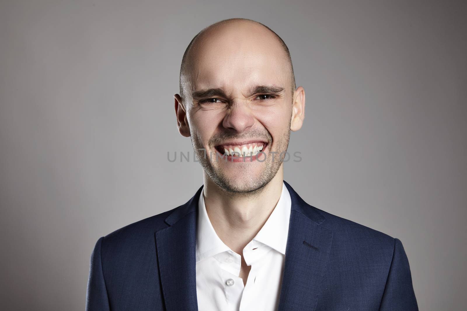 Studio shot of young man looking at the camera. Horizontal format, he is smiling, he is wearing a black jacket.