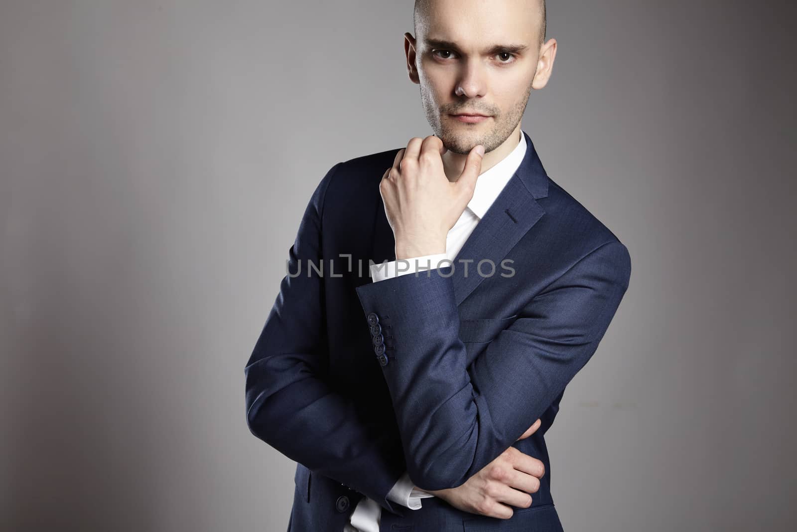 Portrait of young pensive businessman on gray background.