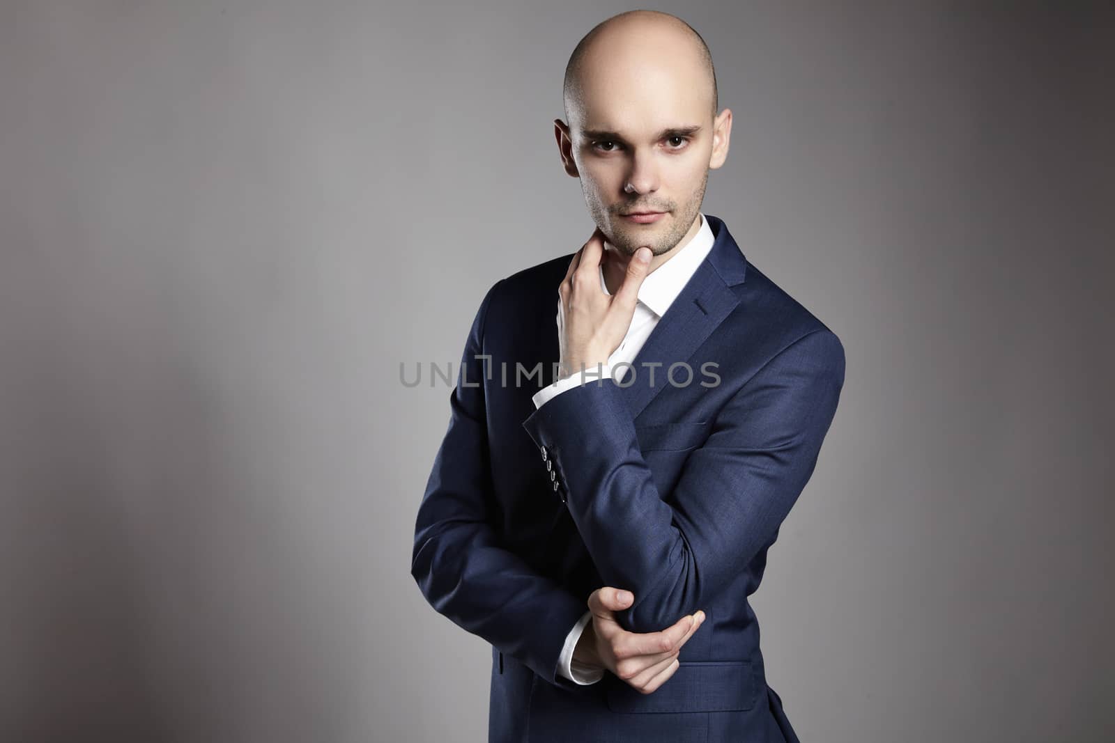 Portrait of young pensive businessman on gray background.