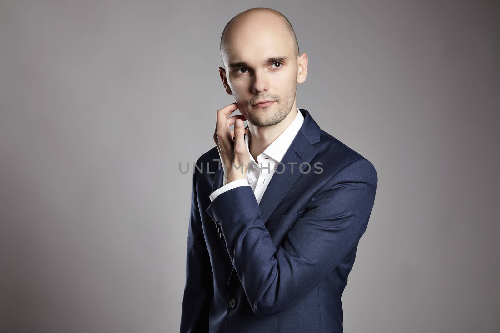 Portrait of young pensive businessman on gray background.