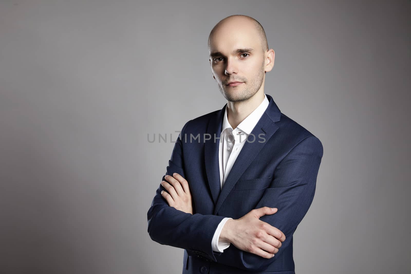 Portrait of young pensive businessman on gray background.