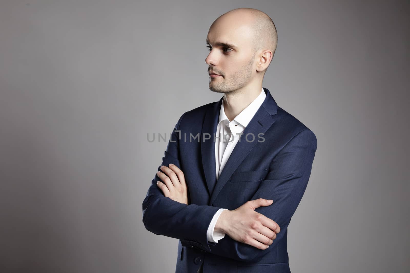 Side view of young man wearing suit on gray background. He is serious.