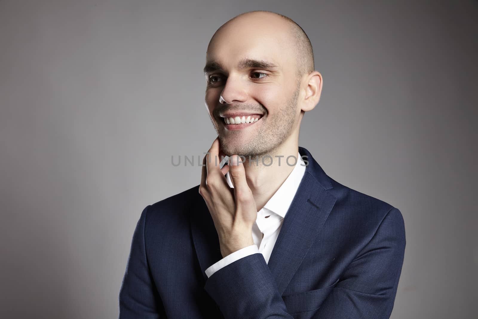 Portrait of a smiling man looking right. He is stroking his chin.