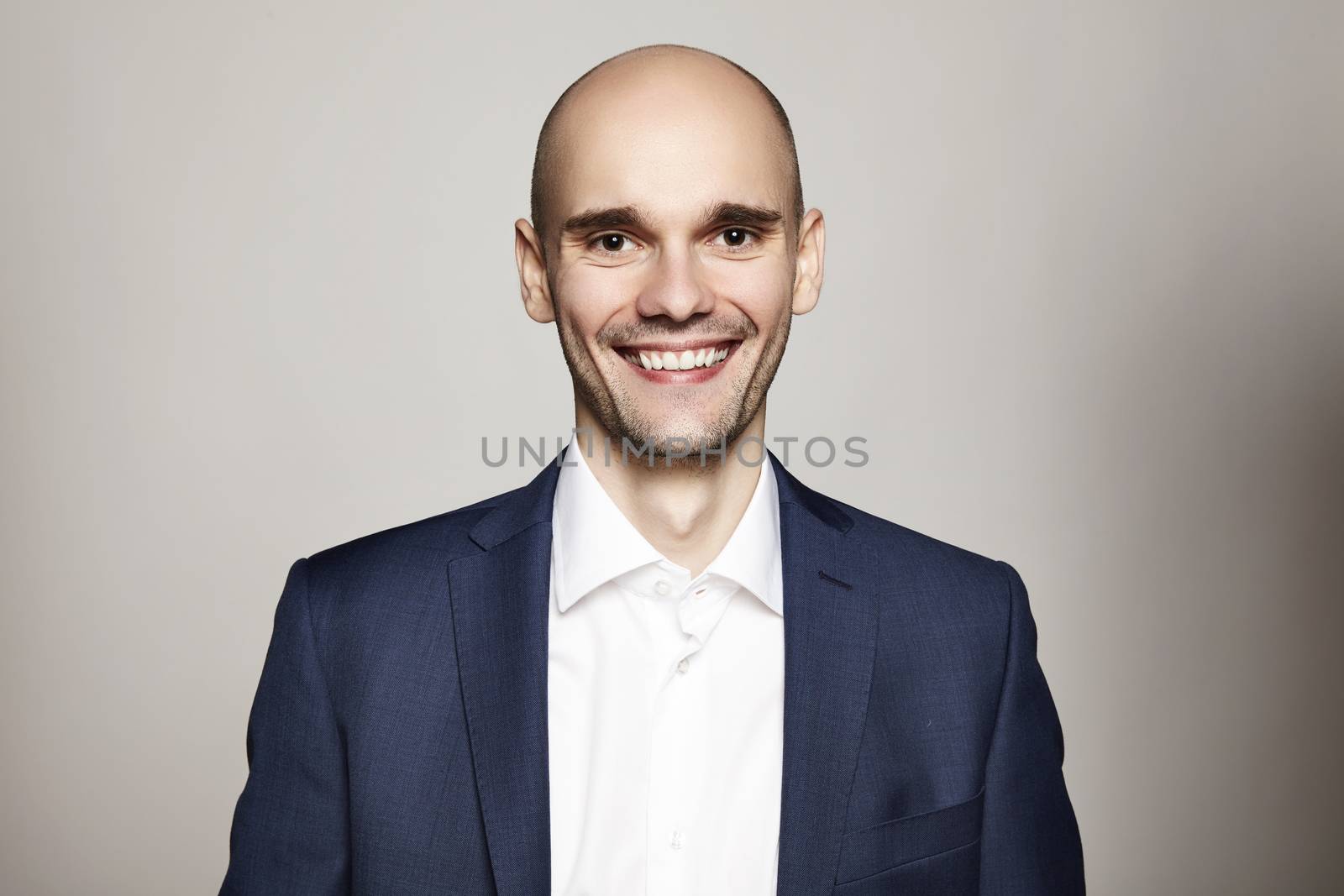 Portrait of young smiling man on gray background.