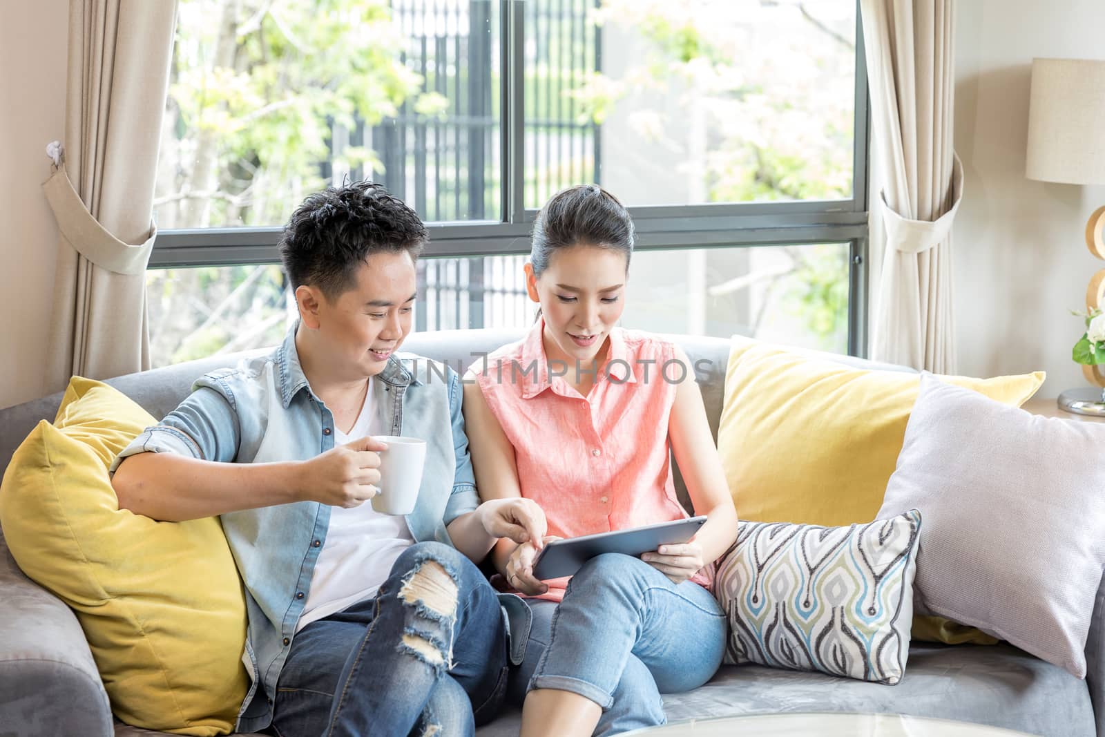 Young Couples using tablet tohether in living room of contemporary house for modern lifestyle concept