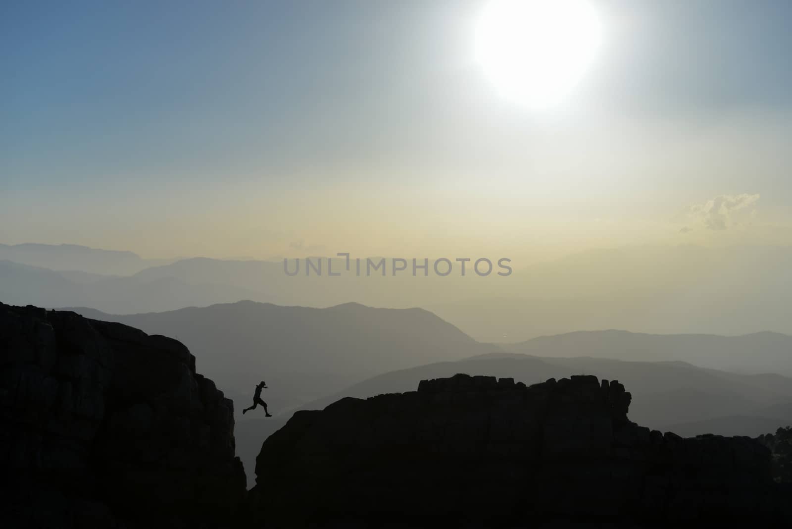 silhouette of the man who jump on the rocks