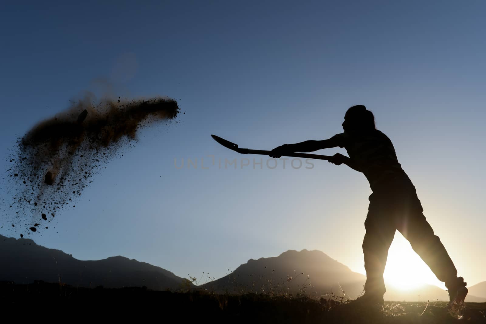 silhouette of a man who the soil with a shovel