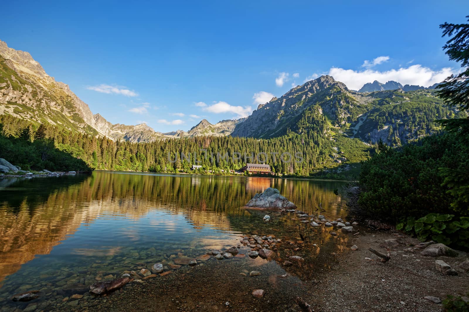 Alpine lake Popradske pleso with touristic shelter - Chata pri popradskom plese, in the morning with a great view on Tatra mountains.