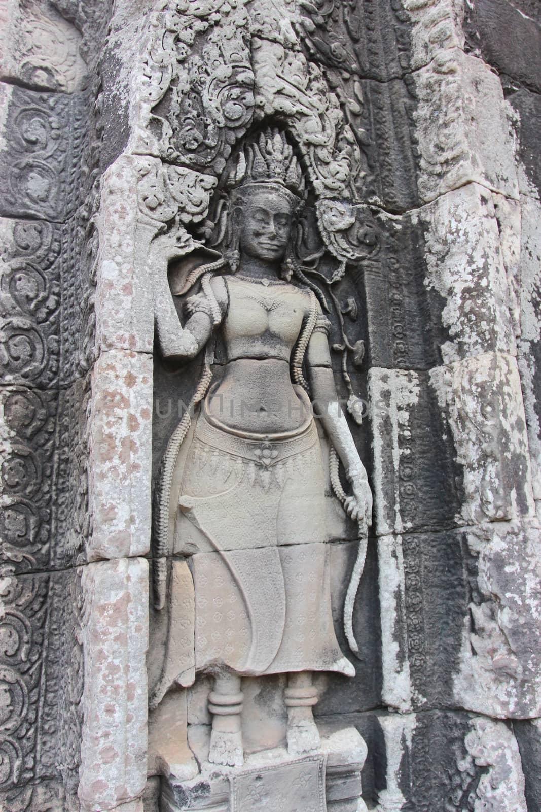 A beautiful ancient relief on the wall of a Cambodian Buddhist temple from Angkor complex, near the antique city of Siem Reap.