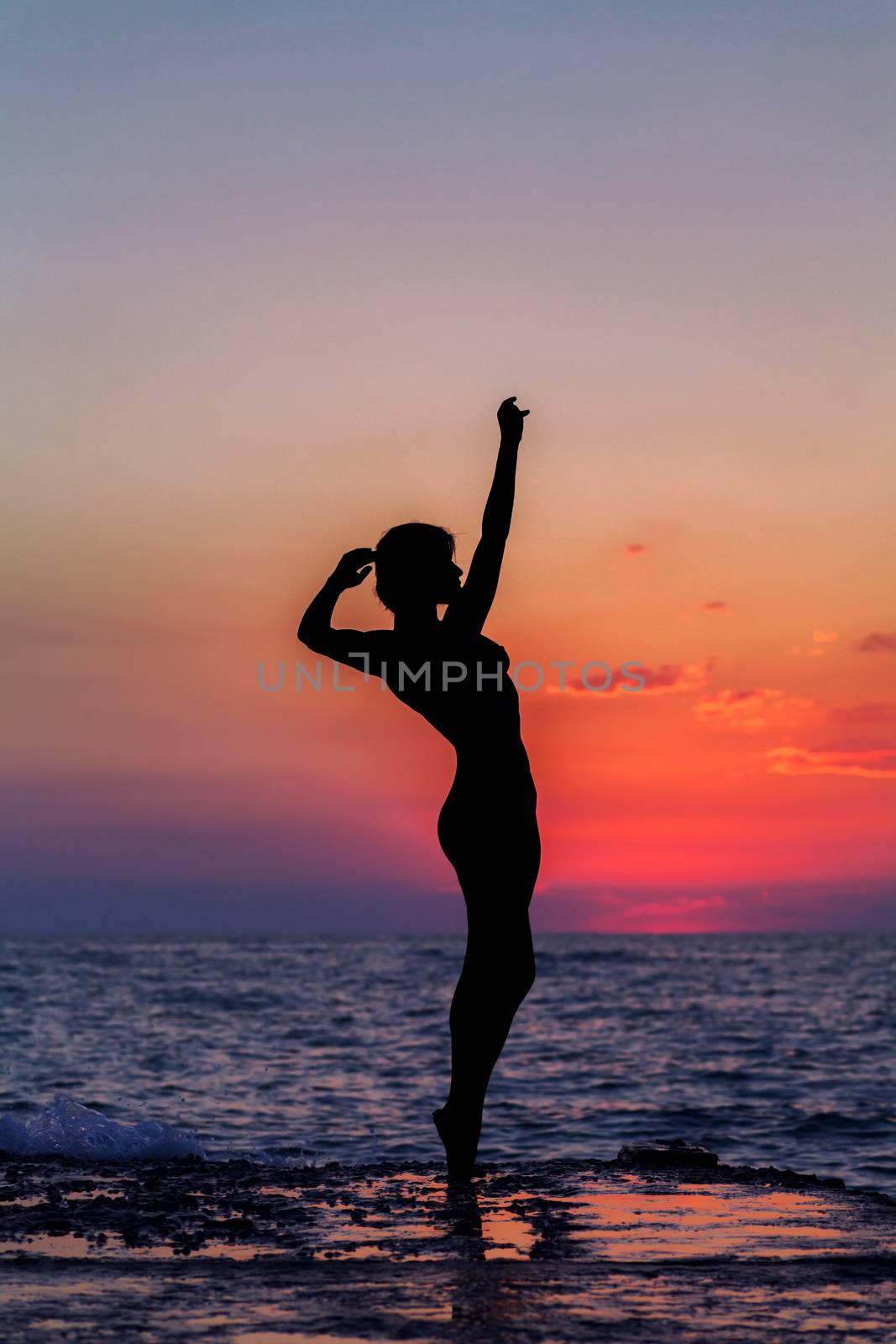 Silhouette of a girl dancing on the background of sea sunset